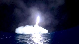 a rocket comes down for a splashdown in the ocean at night