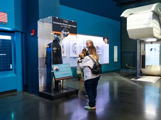 several people look at a flight suit display inside an air and space museum