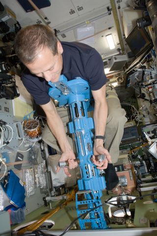 a man in a short sleeved shirt holds onto a blue cylinder with metal handholds