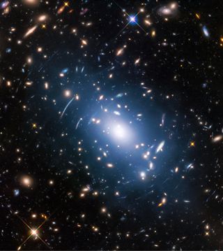 The galaxy cluster Abell S1063, as seen by the NASA/ESA Hubble Space Telescope during the Frontier Fields program. The huge mass of the cluster — containing both normal matter and dark matter — acts as a cosmic magnifying glass, deforming the views of objects behind it. Astronomers have used this gravitational lensing effect to calculate the distribution of dark matter in galaxy clusters. Another way of doing this is to study the intracluster light (visible in blue), which follows the distribution of dark matter.