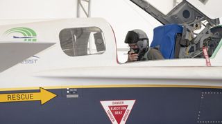 a white jet sits in a hangar in the desert