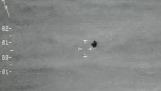 a grainy black orb above the ocean in a black-and-white video