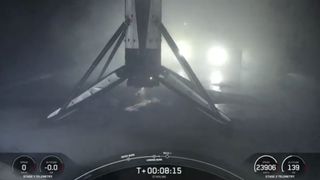 A black and white spacex falcon 9 rocket first stage sits on the deck of a ship at sea.