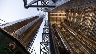 ground-level view looking up at a huge silver rocket leaving a hangar that still has two rockets inside