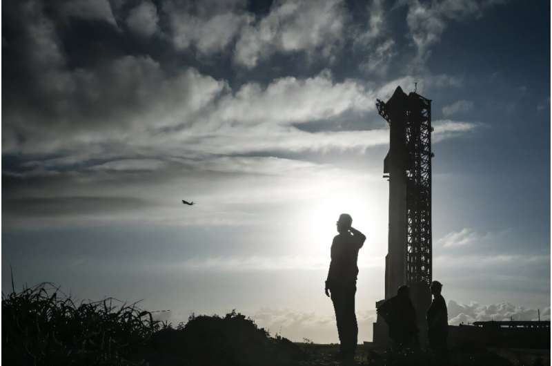 A man watches a SpaceX plane as it flies past the SpaceX Starship at the launch pad ahead of its sixth flight test from Starbase in Boca Chica, Texas