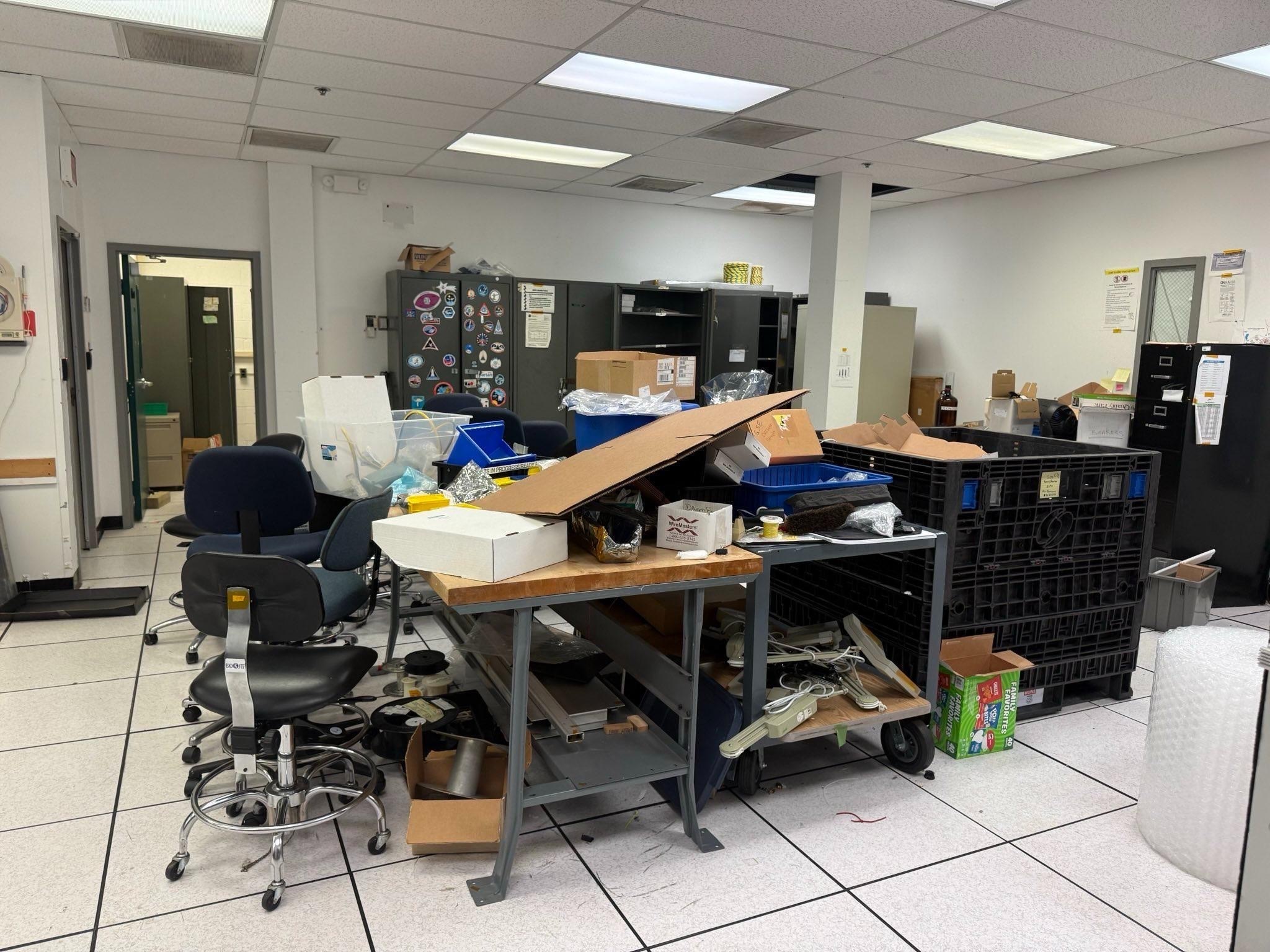 Various office spaces including desks, shelves and warehouses full of items stacked ready to be removed. 