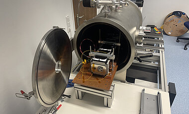 A round metal tube is opened on one end, showing various instruments inside.