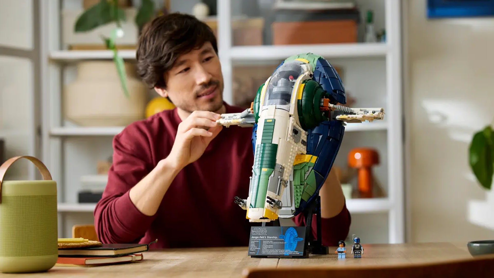 A man adjusting the wing of a Lego Star Wars Jango Fett starship