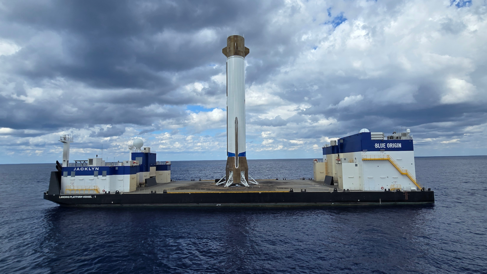 a white rocket booster stands upright on a barge