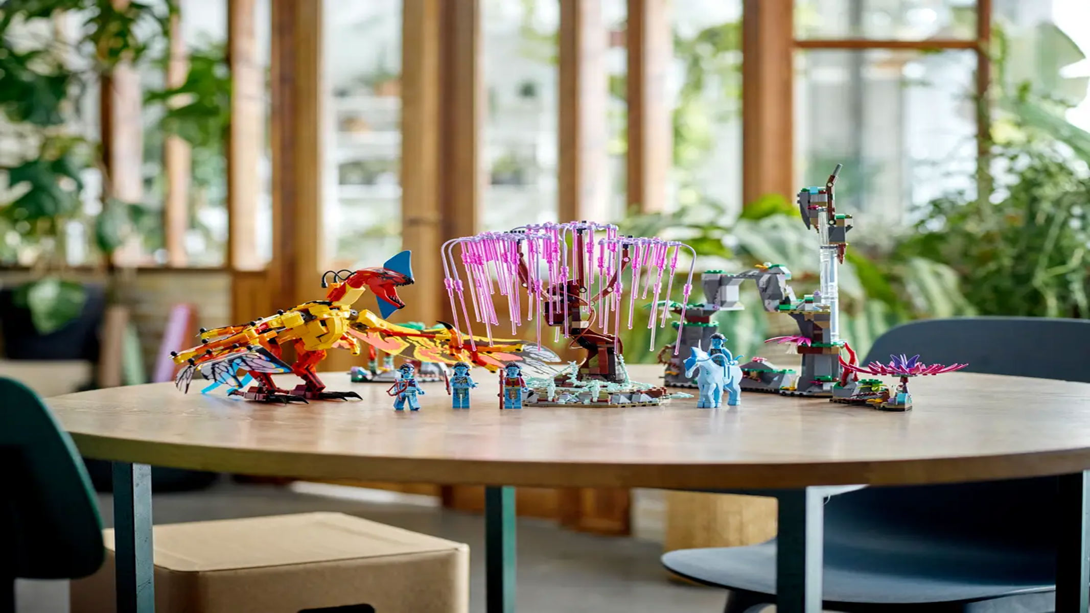 A brick-built tree with pink droopy branches sits among several characters on a brown wooden table.