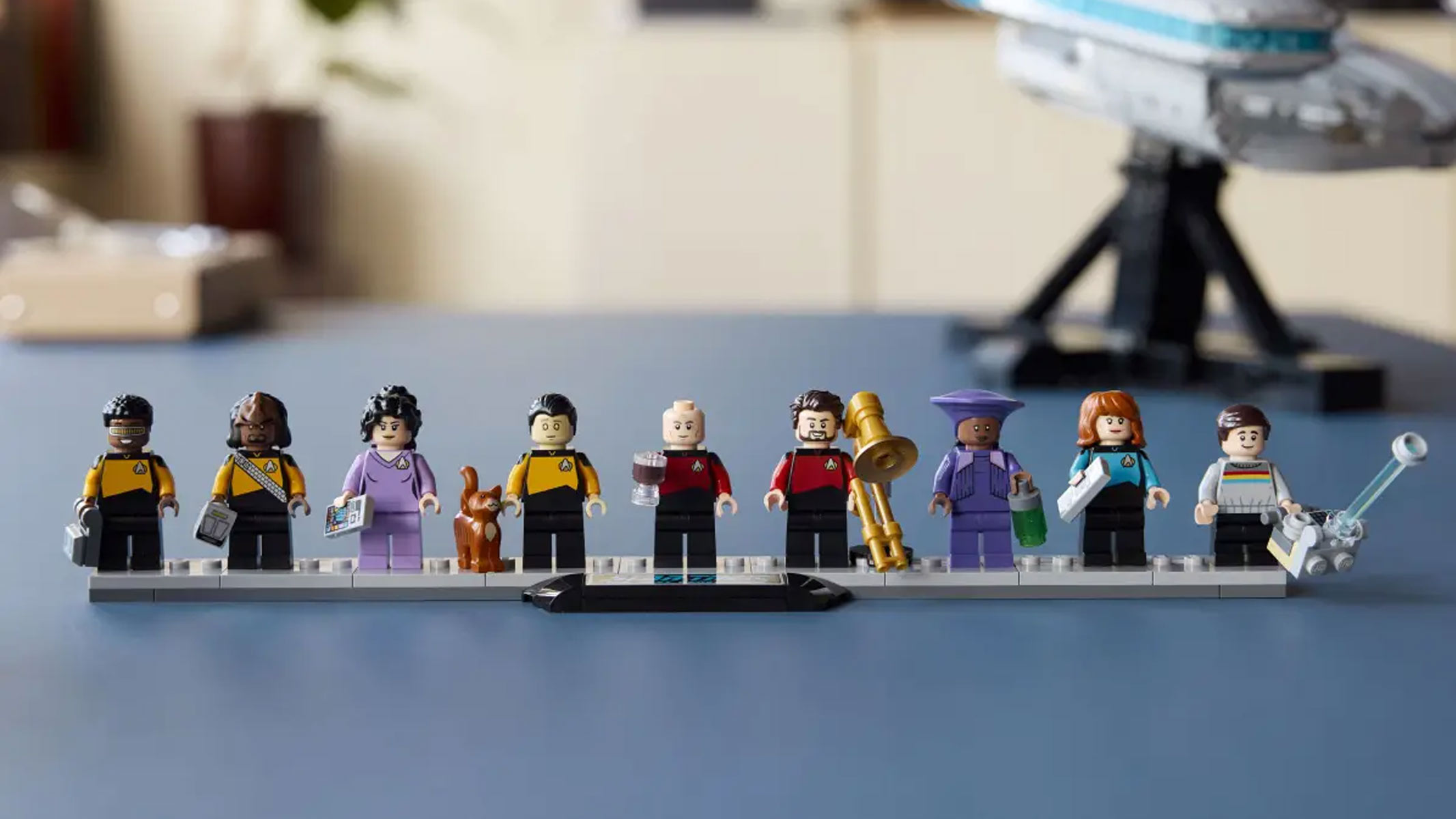 A grey brick-built spaceship is displayed with minifigures and an information plaque.