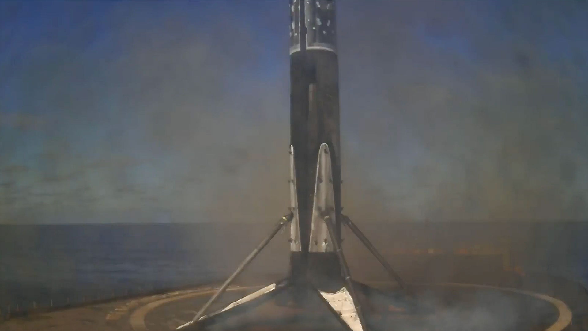 a rocket's first stage stands on its four deployed landing legs after touching down on a droneship positioned in the ocean
