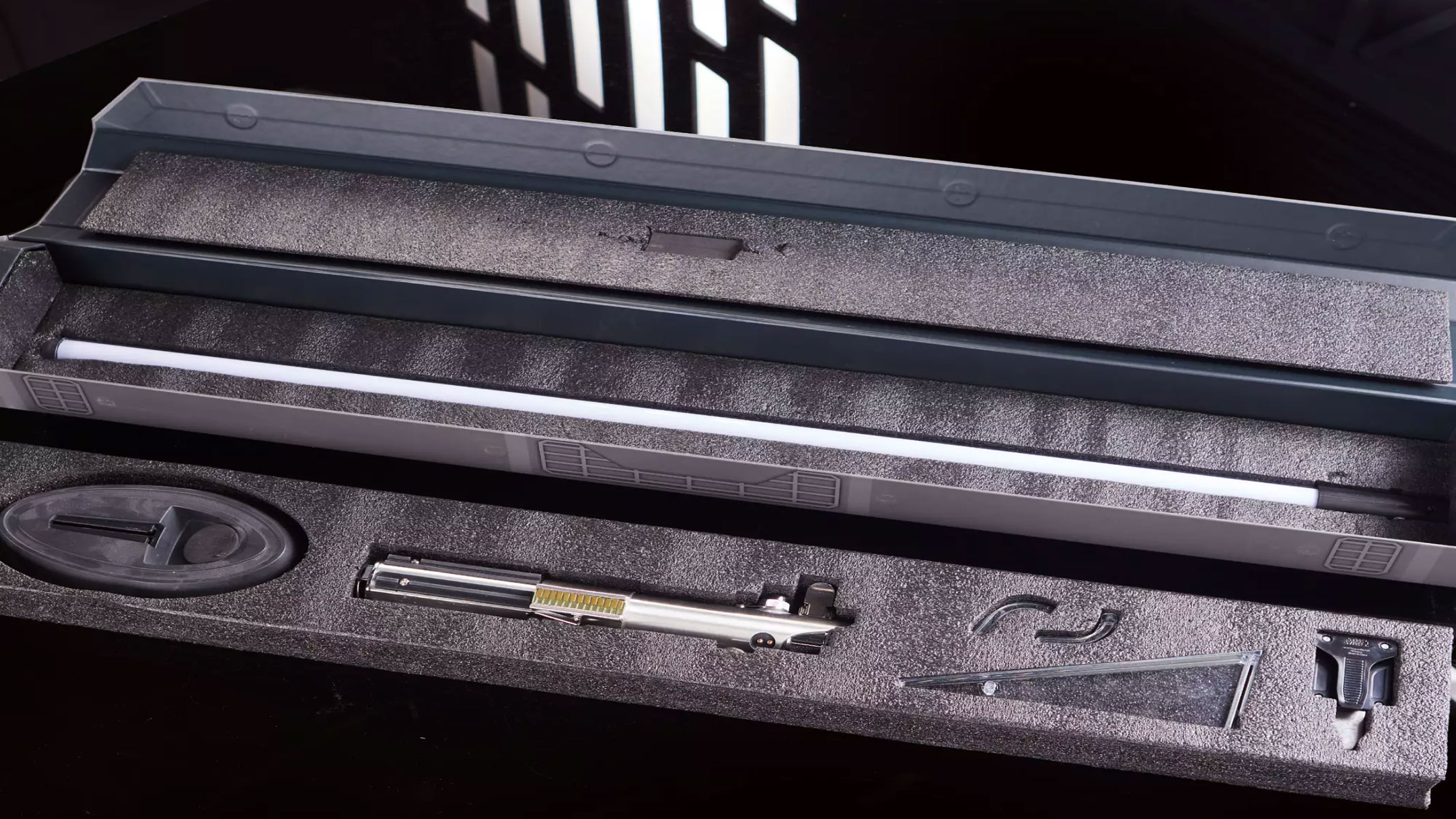 A silver metal hilt is on display as a blue lightsaber is on a black background.