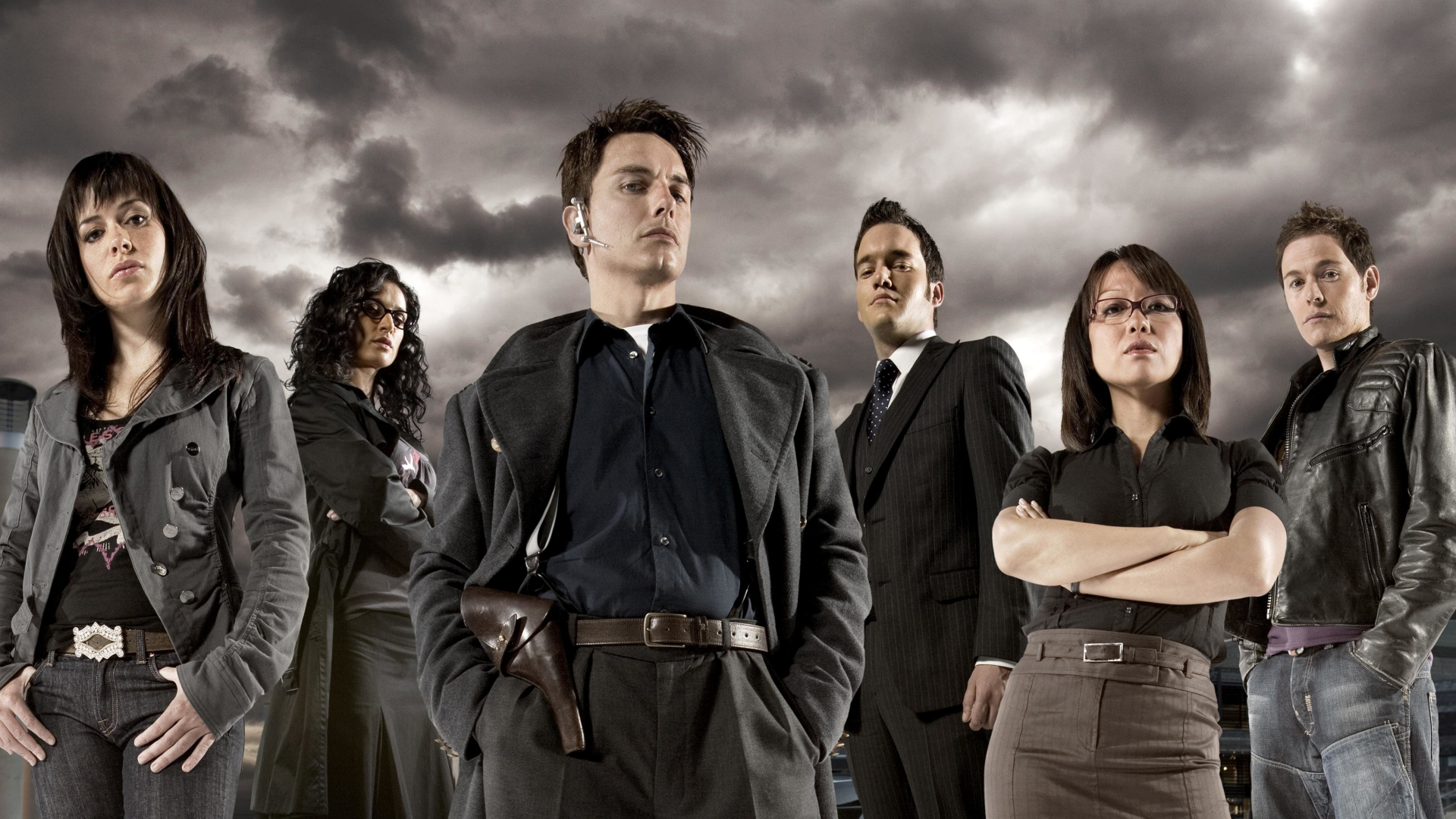 The cast of Torchwood: Children of Earth standing in front of a cloudy sky.
