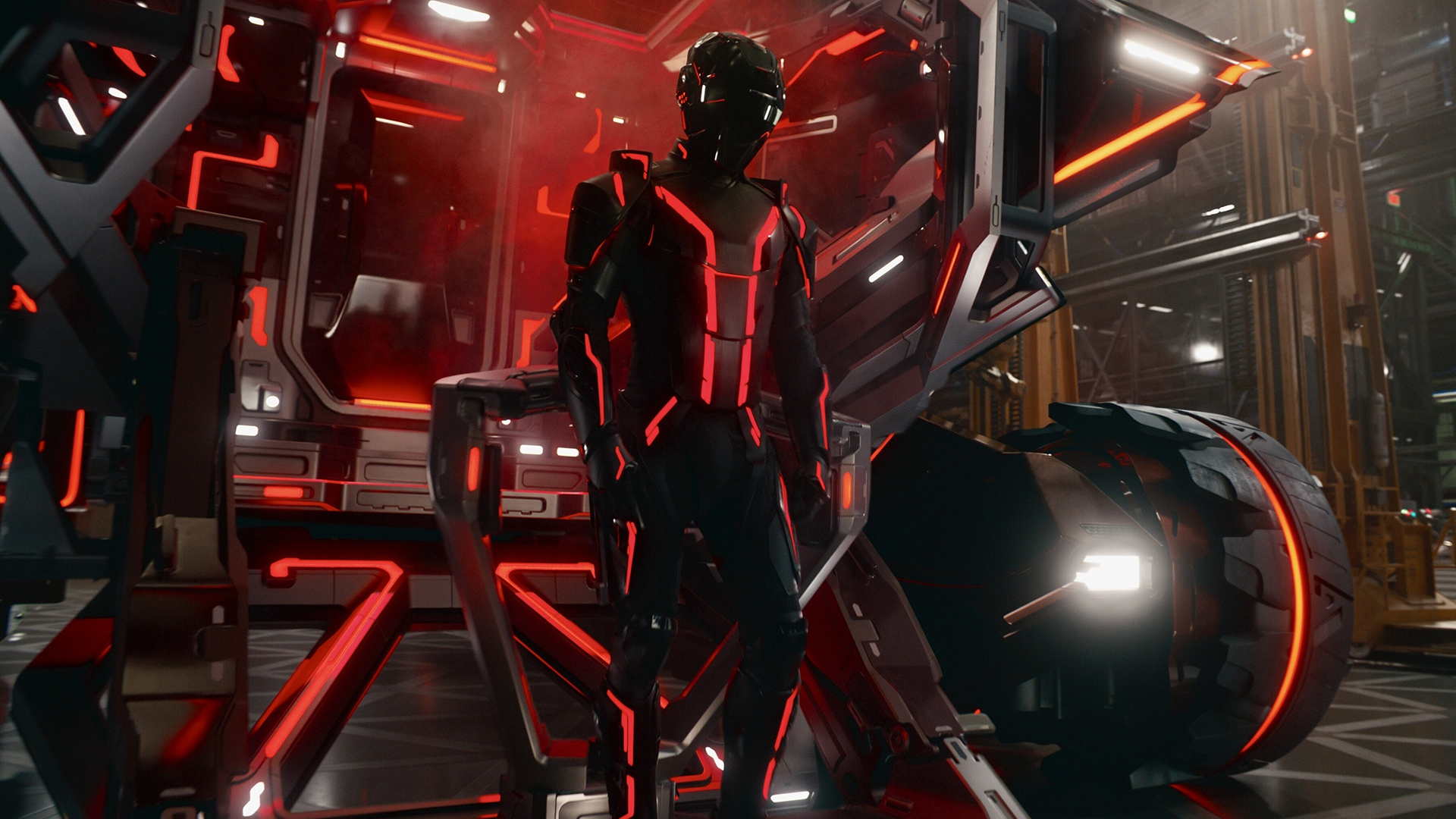 Still from the movie Tron: Ares. A person wearing a black bodysuit and helmet (both trimmed with red lights) is standing next to a black and red to Light Cycle (futuristic motorcycle). They are standing in a futuristic red black and red hanger.
