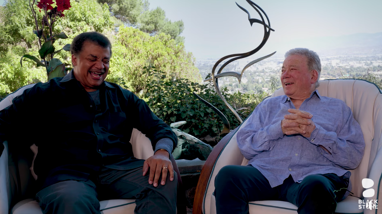 two men sitting in a backyard over looking a city