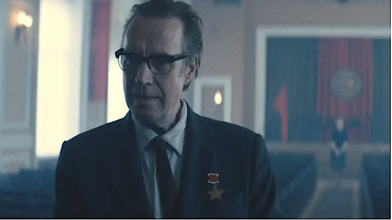 a man in a suit with glasses in an auditorium