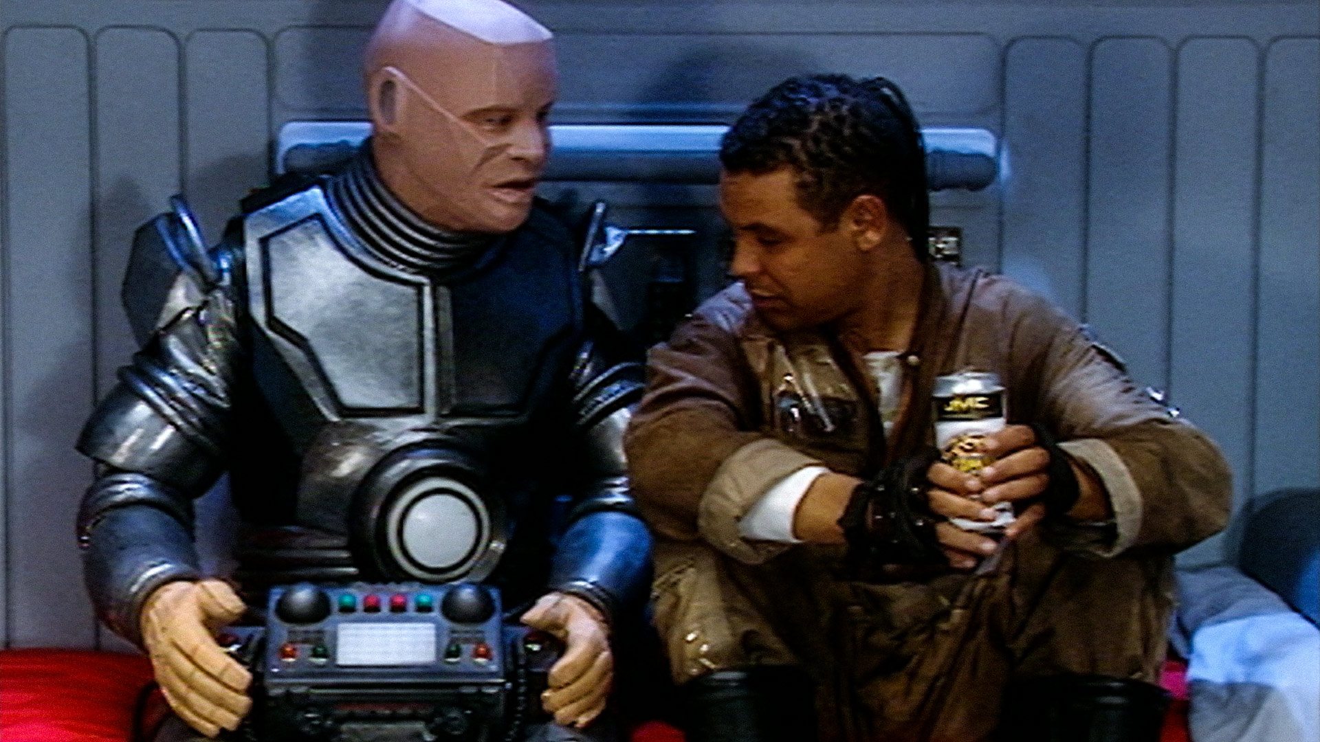 Still from the British sci-fi sitcom called Red Dwarf. From left to right: Kryten and Lister.