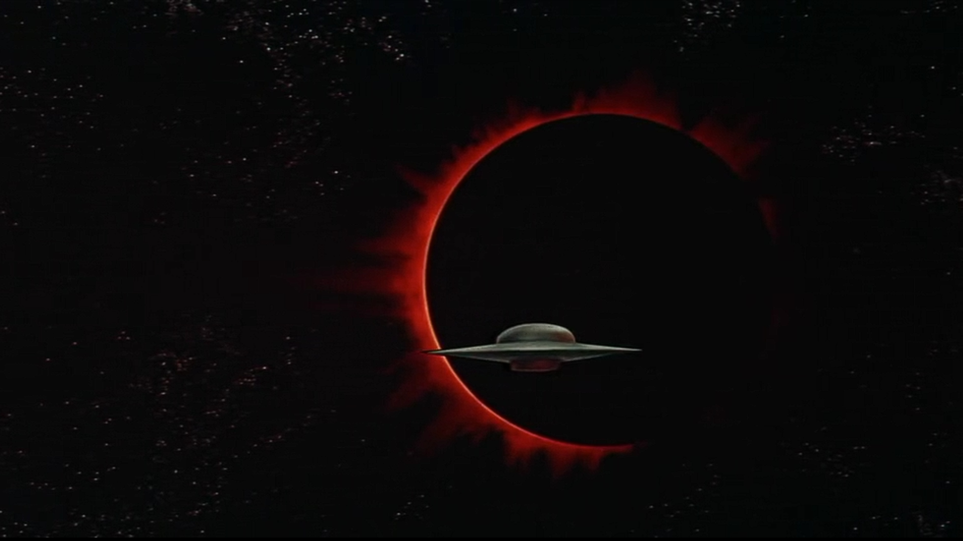 Screenshot from the 1956 sci-fi movie Forbidden Planet, showing a UFO against the dark background of an eclipse.