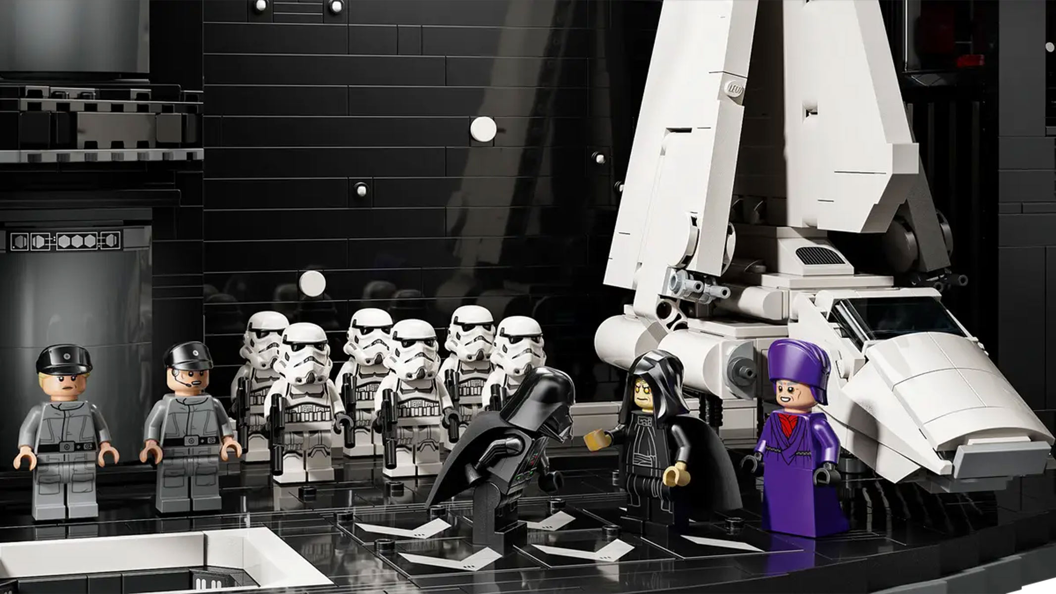 Stormtrooper minifigures are lined up in front of Darth Vader and the Emperor next to an Imperial shuttle, all in brick-built hangar.