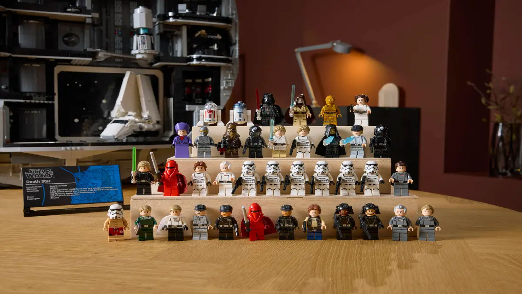 A series of minifigures are lined up in a pyramid formation in front of the brick-built Death Star.