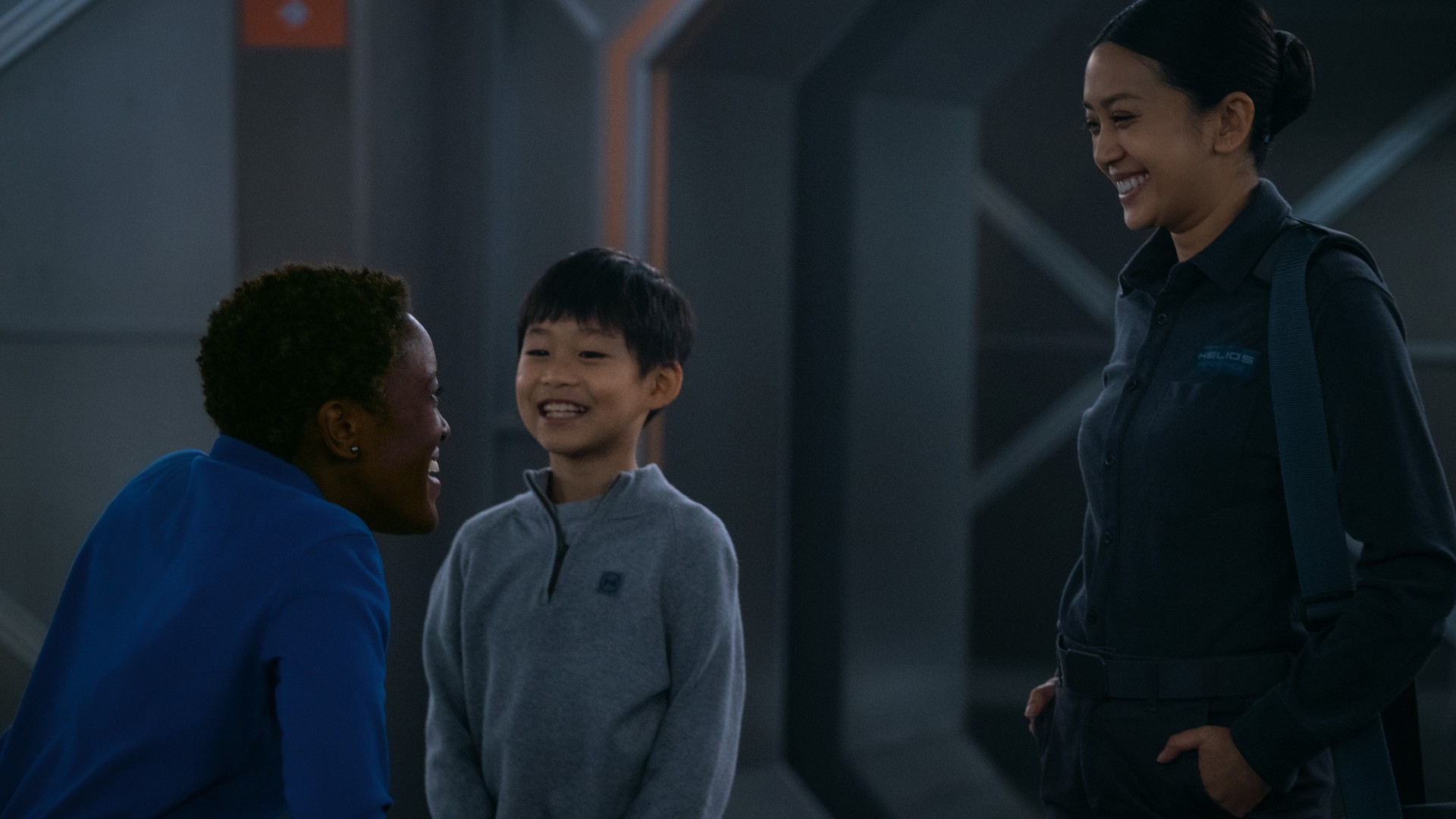 A young boy and mother are smiling at the happy woman crouching to greet the boy.