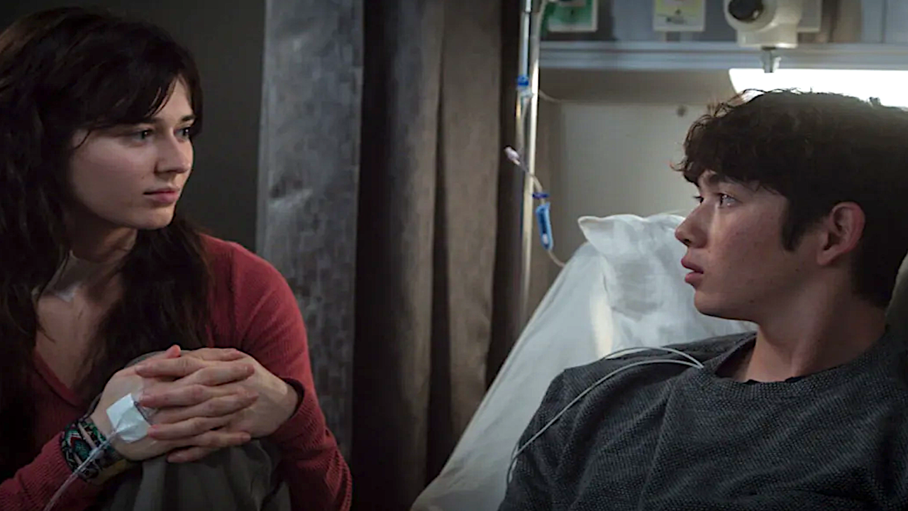 a young woman sitting beside a young man in the hospital